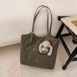 Detail of olive green vintage tote bag with gold logo and fluffy rabbit charm