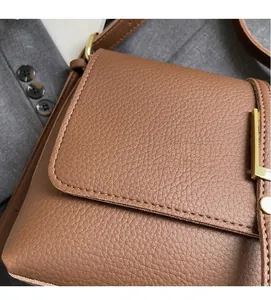 Detailed macro view of brown lychee grain leather handbag with gold metal hardware