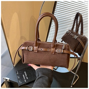 Detail of a brown suede cylinder handbag with leather straps and silver metal buckle