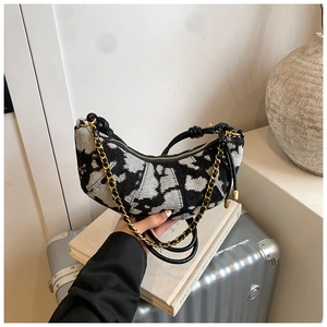 Detail of black and white jacquard crescent bag with gold chain and logo pattern