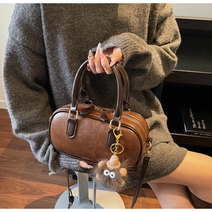Brown vintage faux leather boston bag with adjustable strap and cute monster charm detail