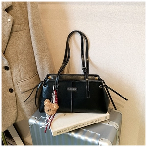 Close-up of black tote bag with white contrast stitching and cute brown bear charm