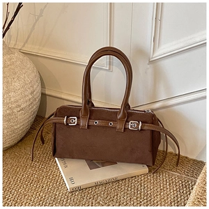 Detail of dark brown suede pillow bag with polished handles and silver metal buckles