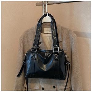 Detail of glossy black PU leather tote bag with silver zippers and detachable strap