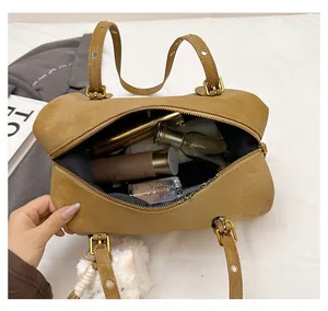 Detail view of spacious interior of brown Boston bag filled with cosmetic essentials