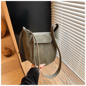 Detail of olive green bucket bag with white stitching and pebbled leather texture