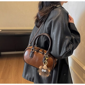 Braune Boston-Handtasche aus Leder mit runden Griffen und Plüsch-Monster-Anhänger