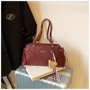 Detail of burgundy leather tote bag with white stitching and fashion metal plate