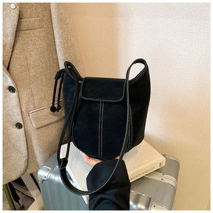 Detail of black suede bucket bag featuring white contrast stitching on a travel case