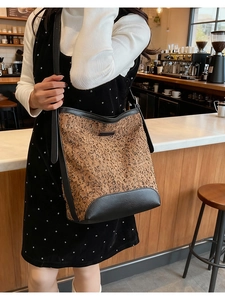 Close-up of leopard print bucket bag with black leather trim and metal logo detail
