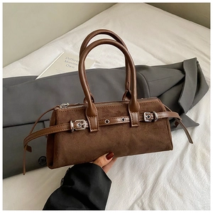 Close-up of brown suede pillow bag with dual handles and decorative silver buckle detail