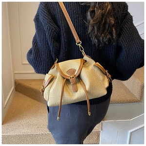 Detail of khaki canvas bucket bag with brown leather trim and drawstring closure