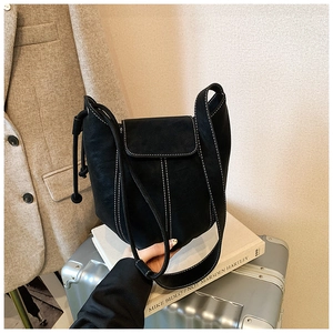 Detail of a black bucket bag with white contrast stitching on a stylish background