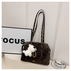 Detail of dark brown suede shoulder bag with bronze hardware and plush puppy pendant