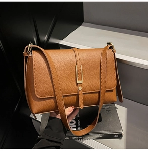 Detailed macro view showing the brown lychee grain texture and gold bar clasp on the bag