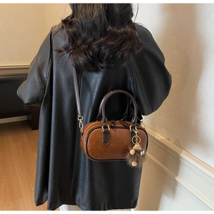 Detailed back view of a vintage brown leather bowling bag with plush eye charm