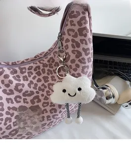 Close-up of a cute white cloud plush pendant hanging on a purple leopard print tote bag