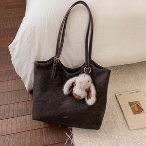 Close-up of vintage brown leather tote bag with gold logo and plush rabbit charm