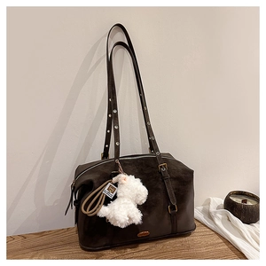 Detail of coffee brown suede shoulder bag with eyelet straps and plush dog charm
