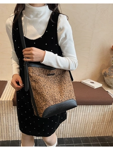 Detailed view of leopard print bucket bag with black leather trim and adjustable strap