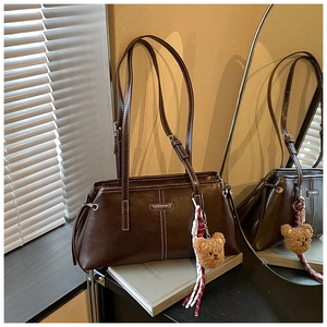 Detail of retro dark brown tote bag with contrast stitching and plush bear charm