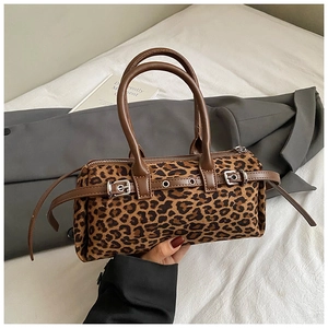 Detailed close-up of leopard print cylinder bag with brown leather straps and metal buckle