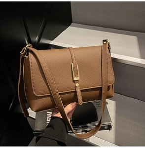 Detail of vintage brown pebble leather shoulder bag with sleek gold metal buckle