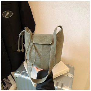 Sage green bucket bag with contrast white stitching and drawstring on lychee leather texture