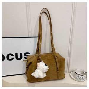 Close-up of camel suede tote bag with metal logo, leather trim and plush puppy charm