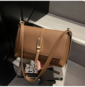 Detail of brown lychee texture leather bag with elegant gold hardware on stone background