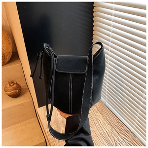 Detail of black bucket bag with contrast white stitching and decorative side tassels