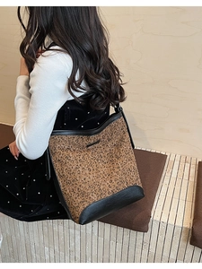Detail of leopard print bucket bag with black leather trim worn on the shoulder