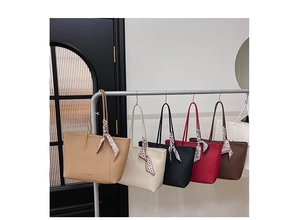 Five assorted tote bags in various colors hanging with decorative scarves on silver hangers