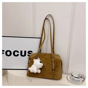 Detail view of brown matte shoulder bag featuring adjustable straps and plush dog charm