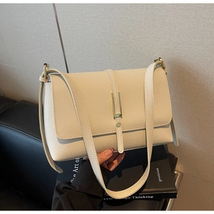 Detail of off-white lychee grain leather handbag with gold bar clasp and flap cover