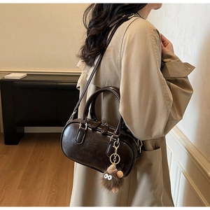 Detail shot of a dark brown retro leather handbag worn with a khaki trench coat