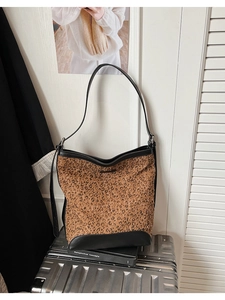 Detail of leopard print bucket bag featuring black leather trim on a metal suitcase