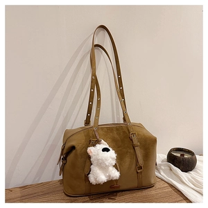 Detail view of retro khaki shoulder bag with metal eyelet straps and plush dog charm