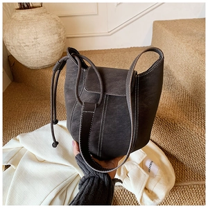 Close-up of dark grey bucket bag with white stitching and drawstring closure