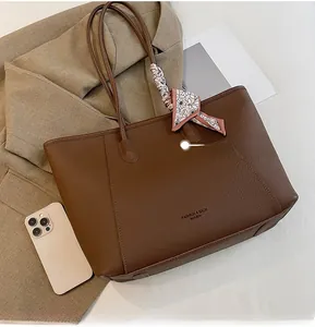 Close-up of brown pebbled tote bag featuring floral scarf detail and brand logo print
