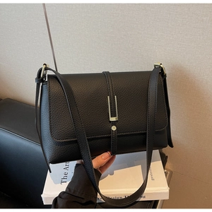 Detailed view of the black lychee pattern leather finish and gold metal buckle on the bag