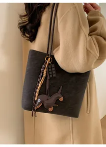 Detail of matte dark brown tote bag with decorative charms on a wool coat model