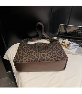 Detail view of large leopard print tote bag with brown leather trim and laptop accessories
