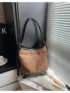 Macro detail of leopard print sequin bucket bag with black leather trim and metal logo