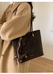 Detail of dark brown leather tote bag with gold lettering and dachshund charm