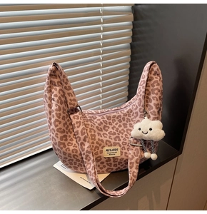Close-up of leopard print canvas tote bag with shoulder strap and plush cloud pendant