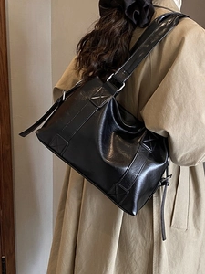 Vintage black faux leather tote bag for women shown on a model in a trench coat