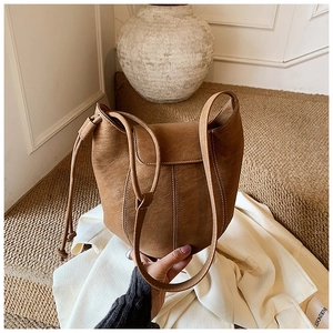 Detail of dark camel bucket bag featuring contrast stitching and soft leather texture