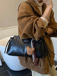 Minimalist black leather tote bag with white stitching and plush bear charm for women