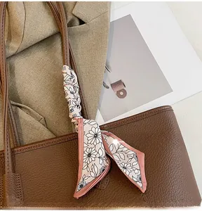 Close-up of pink floral silk scarf wrapped around a dark brown tote bag handle